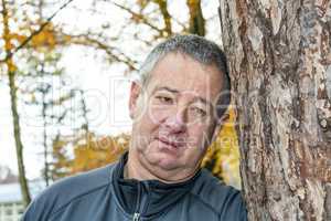 Man leans against tree to rest