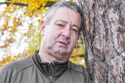 Man leans against tree to rest