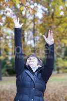 Woman stretches herself and hops with joy in the autumn wood