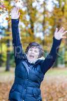 Woman stretches herself and hops with joy in the autumn wood