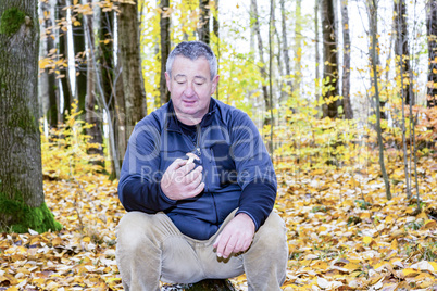 Man sits in the autumn wood on tree stump