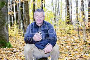 Man sits in the autumn wood on tree stump