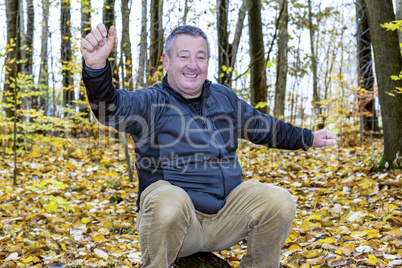 Man sits in the autumn wood on tree stump