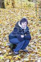 Woman sits in the autumn wood on tree stump