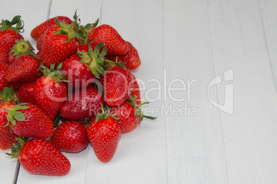 pile of ripe red strawberries on a white surface, empty space on