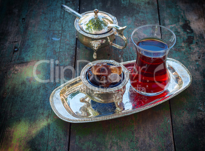 Black tea Turkish glass with slices of sugar on a silver platter