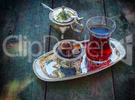 Black tea Turkish glass with slices of sugar on a silver platter