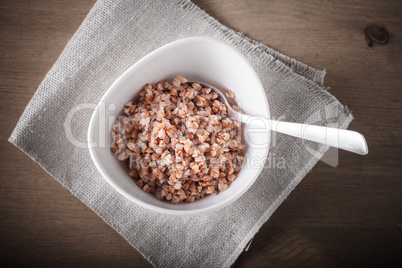 Boiled buckwheat with spoon in ceramic bowl