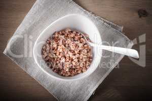 Boiled buckwheat with spoon in ceramic bowl