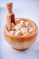 Brown cane sugar cubes in a wooden bowl