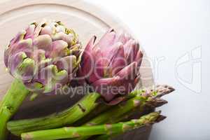 Artichokes and asparagus on a wooden board