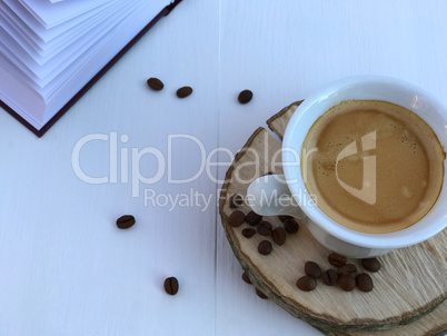 cup of coffee and open book on a white wooden background