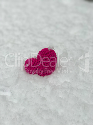 Knitted small heart on the white snow