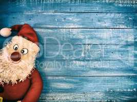 Vintage background with a doll of Santa Claus on a blue wooden b