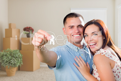 Young Military Couple with House Keys in Empty Room with Packed