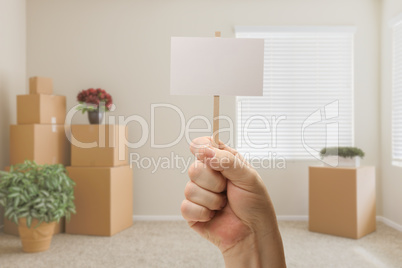 Hand Holding Blank Sign in Empty Room with Packed Moving Boxes