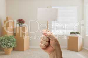 Hand Holding Blank Sign in Empty Room with Packed Moving Boxes