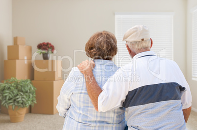 Senior Couple Facing Empty Room with Packed Moving Boxes and Pot