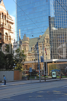 Reflection of old city hall in high rise.