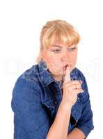 Closeup of blond woman with finger over mouth.