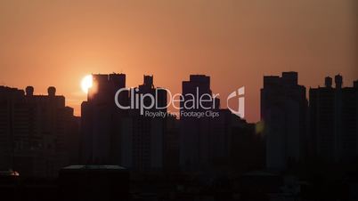 Time lapse shot of sun rising and moving in the sky, city modern buildings on the foreground. Seoul, South Korea