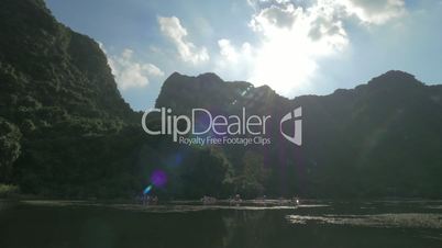 Sun over the islets and touristic boat sailing in Ha Long Bay, Vietnam