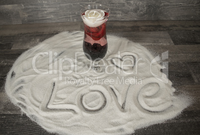 Glas mit Rose und Liebesbekundung im Sand