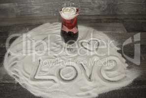 Glas mit Rose und Liebesbekundung im Sand