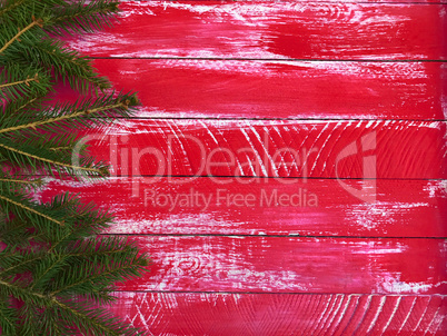 Red wood background with spruce branches on the right and an emp
