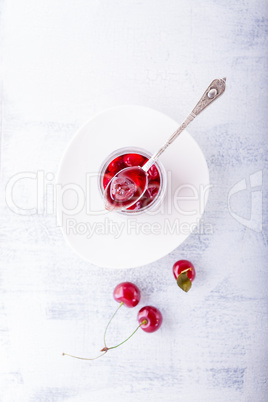 Jar of cherry jam and some cherries on the table