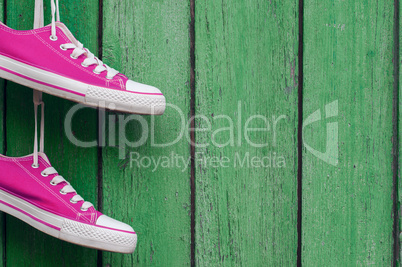 pair of bright pink sports sneakers hanging on a wooden wall cra