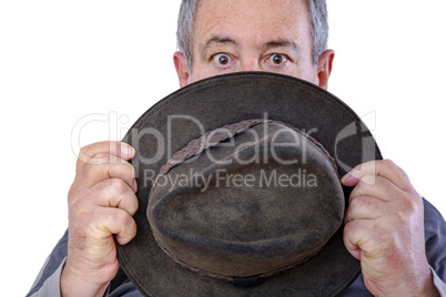 Man is holding a hat in front of his face