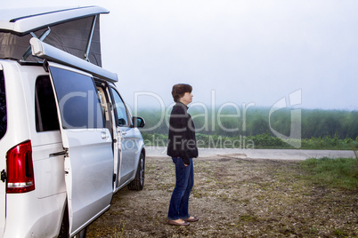 Woman is standing in front of the camping bus