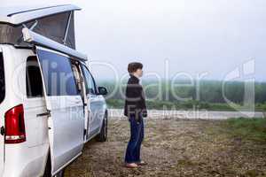 Woman is standing in front of the camping bus