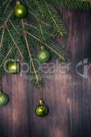 Green branch of fir with Christmas balls on a brown wooden backg