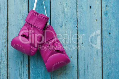 Pink boxing gloves on blue cracked wooden background