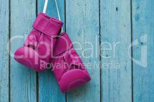 Pink boxing gloves on blue cracked wooden background