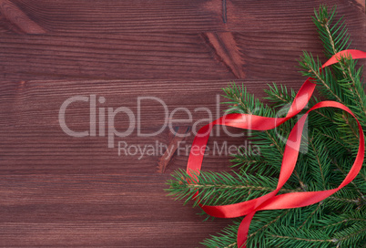 Branch with red ribbon on brown wooden background