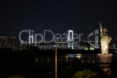 Statue of liberty and Rainbow bridge at night in Odaiba, Tokyo