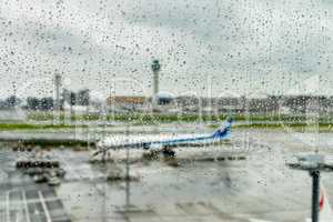 Airplane waiting on runway under rain
