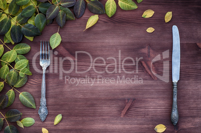 Knife and fork on a brown wooden surface, empty space