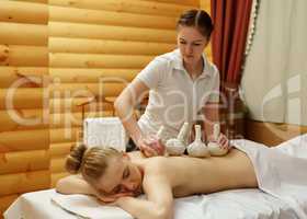 In spa. Masseuse puts salt bags on girl's back