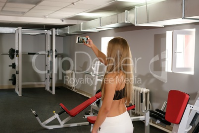 Beautiful girl doing selfie on smartphone in gym