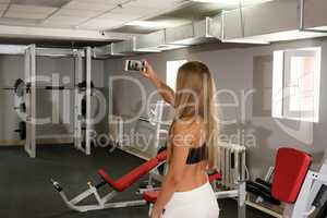 Beautiful girl doing selfie on smartphone in gym