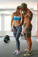 Sporty girl flirting with muscular man in gym