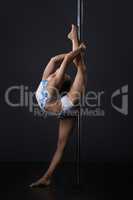 Pole dance in studio. Dancer doing vertical split