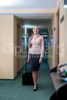 Smiling woman with luggage walks down hallway
