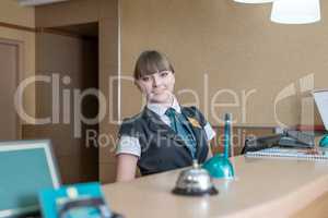 Friendly hotel worker posing behind reception