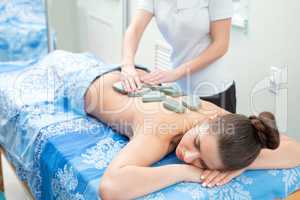 Pretty girl getting hot stone massage in spa salon
