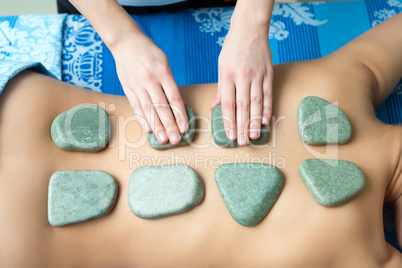 Top view of hot spa stones on girl's back